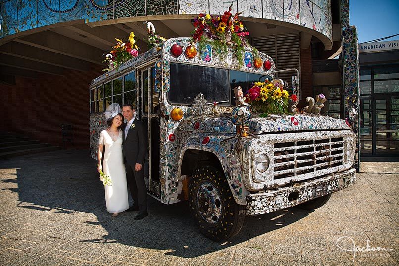 bride and groom in front of visionary decorated bus
