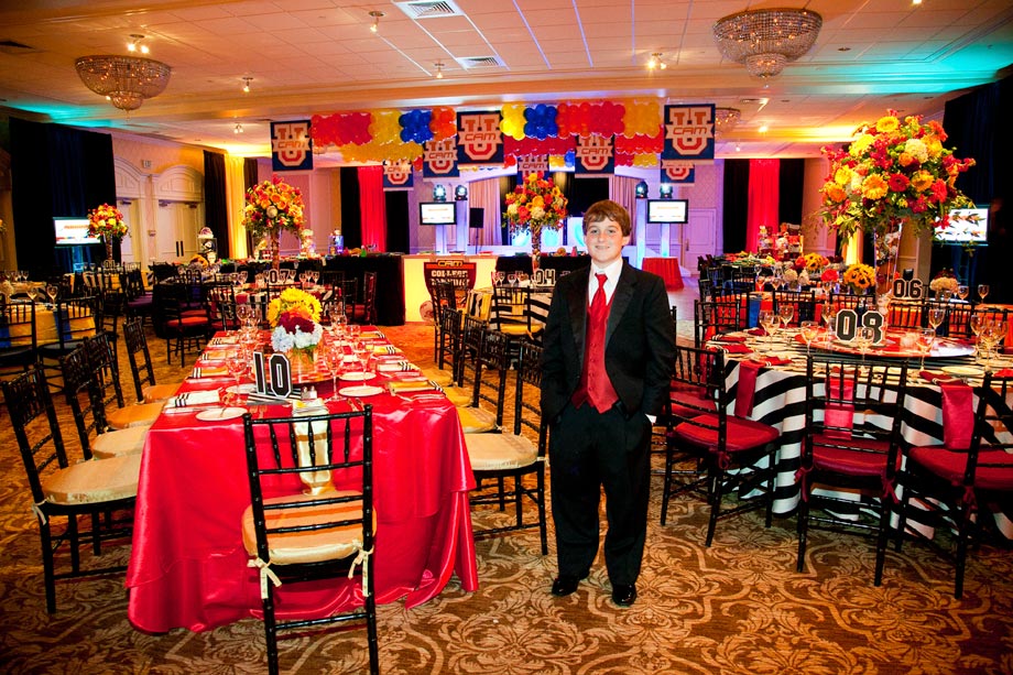 mitzvah boy in front of decorated tables