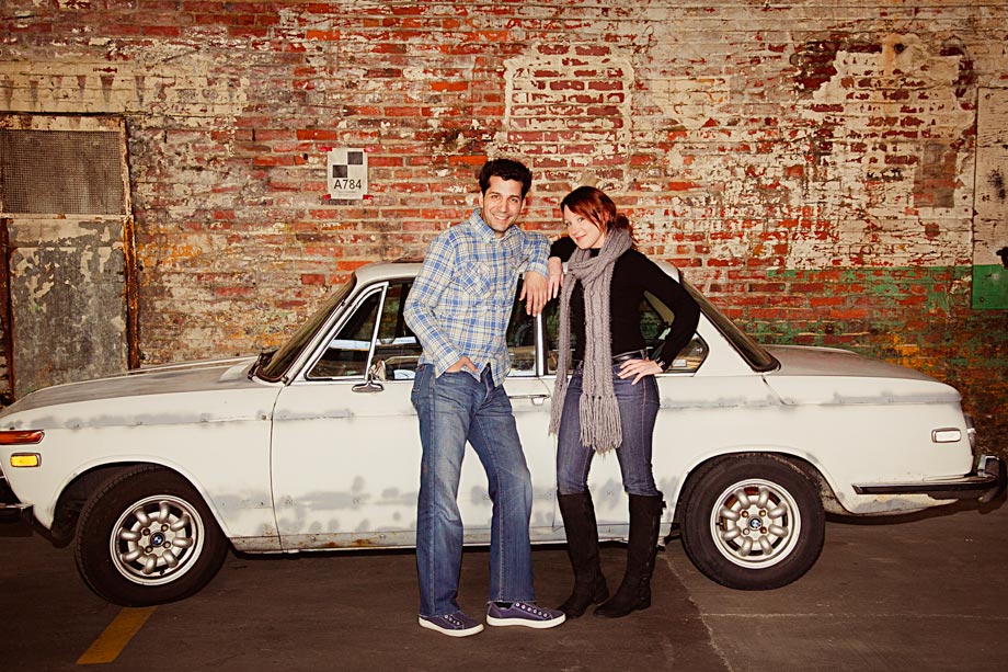 couple posing in front of old car