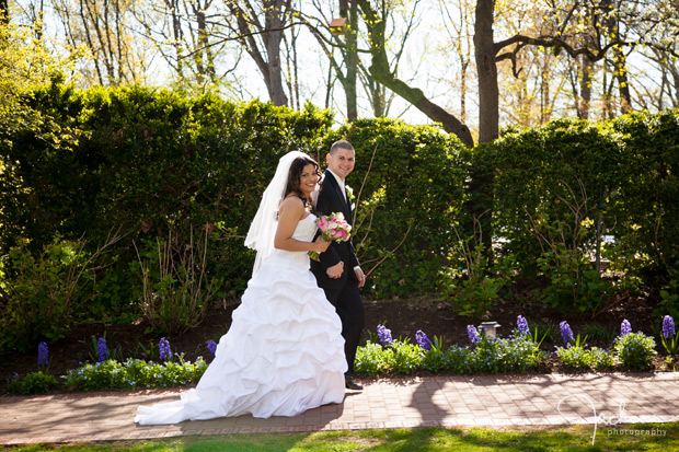bride and groom walking down path by greenery