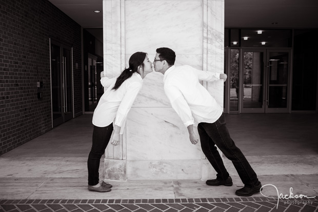 couple kissing around column