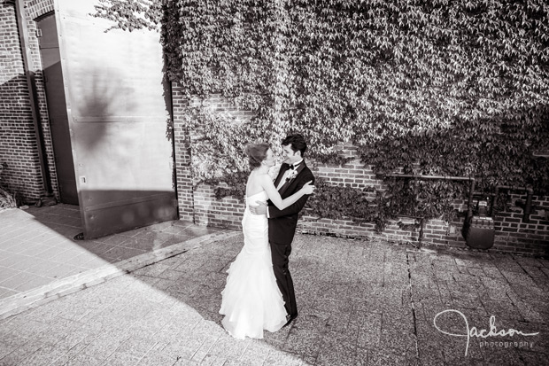 bride and groom embracing by large door of AVAM