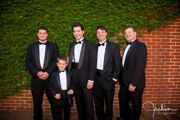 groom and groomsmen in front of ivy brick wall