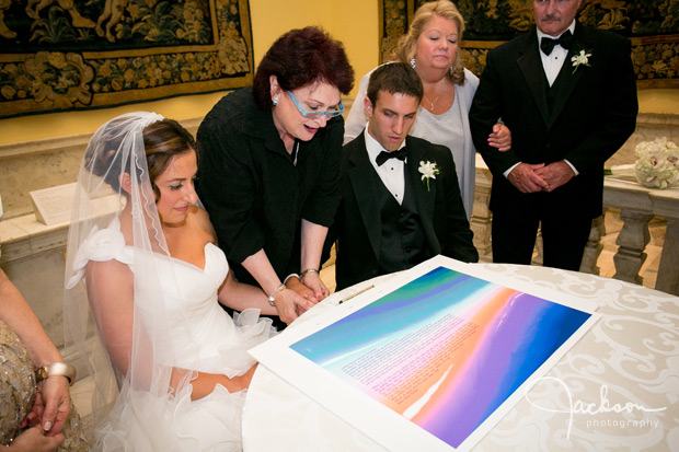 couple signing brightly colored ketubah