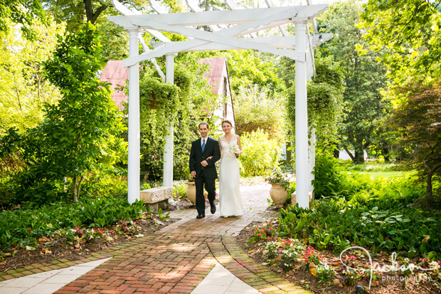 bride and groom walking beneath garden canopy