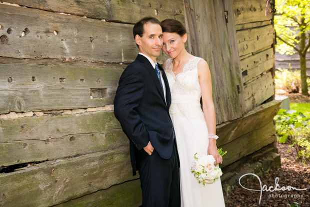 bride and groom leaning on grey barn