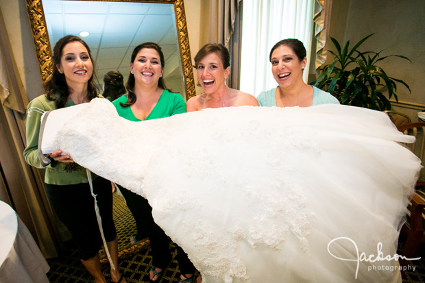Bride and bridesmaids holding the bridal gown