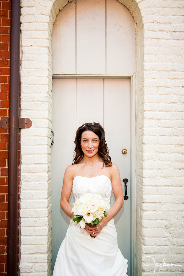 bride in small white brick archway