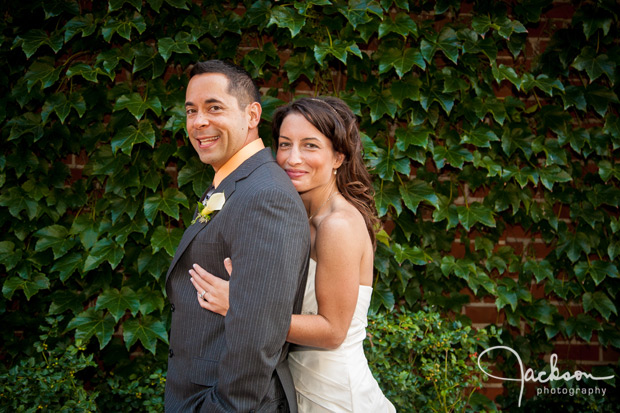 wedding couple hugging and laughing by ivy wall
