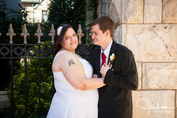 bride and groom by stone church in sunlight