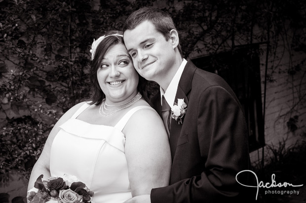 groom kissing bride on cheek black and white photography