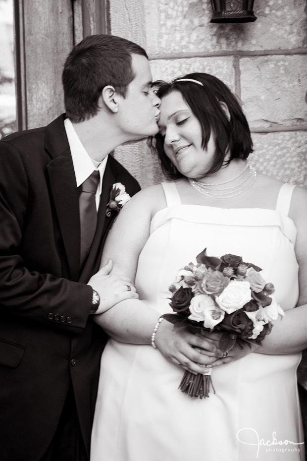 groom kissing bride black and white photography