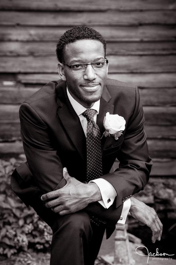 groom in front of rustic barn