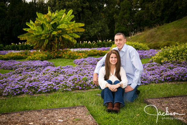 engaged couple sitting in front of garden