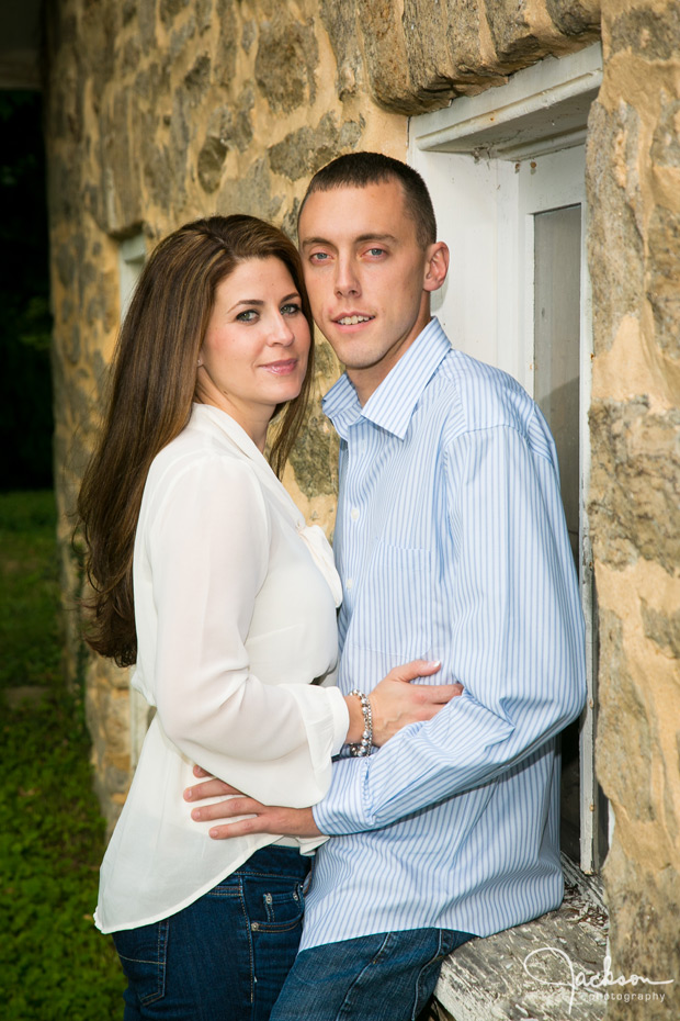 couple leaning against stone wall