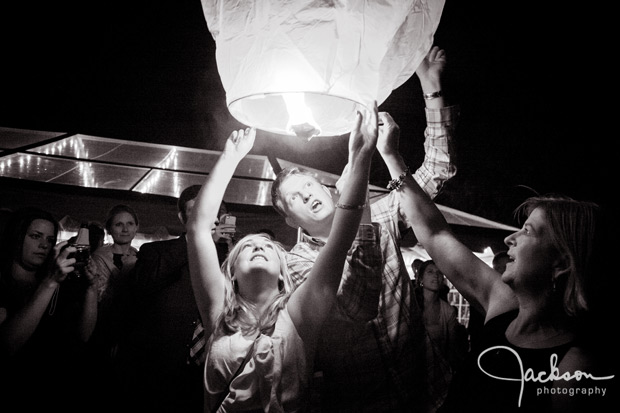 people lighting a paper balloon lantern
