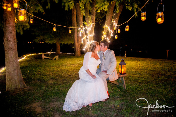 bride and groom kissing under candles hanging from trees