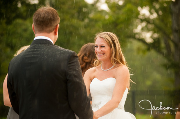 bride smiling during ceremony in the rain