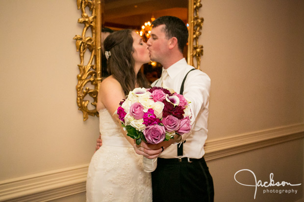 bride and groom kissing while holding flower bouquet