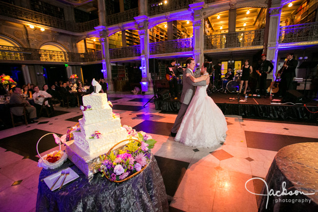 bride and groom first dance by wedding cake