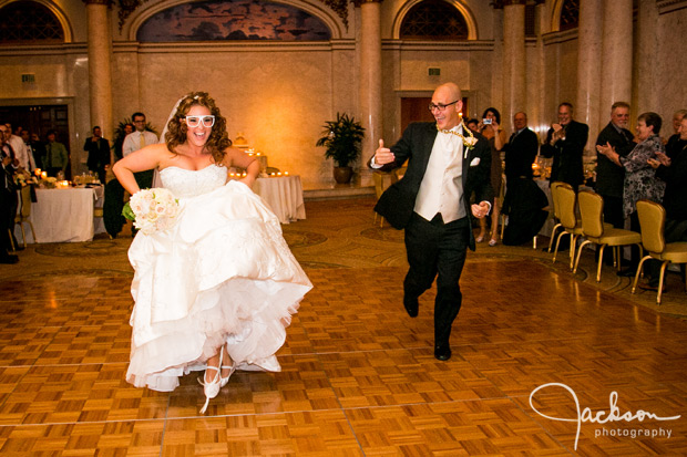 bride and groom entering reception with gold chain and glasses