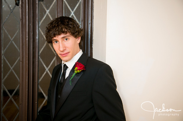 portrait of groom with red rose boutonniere  